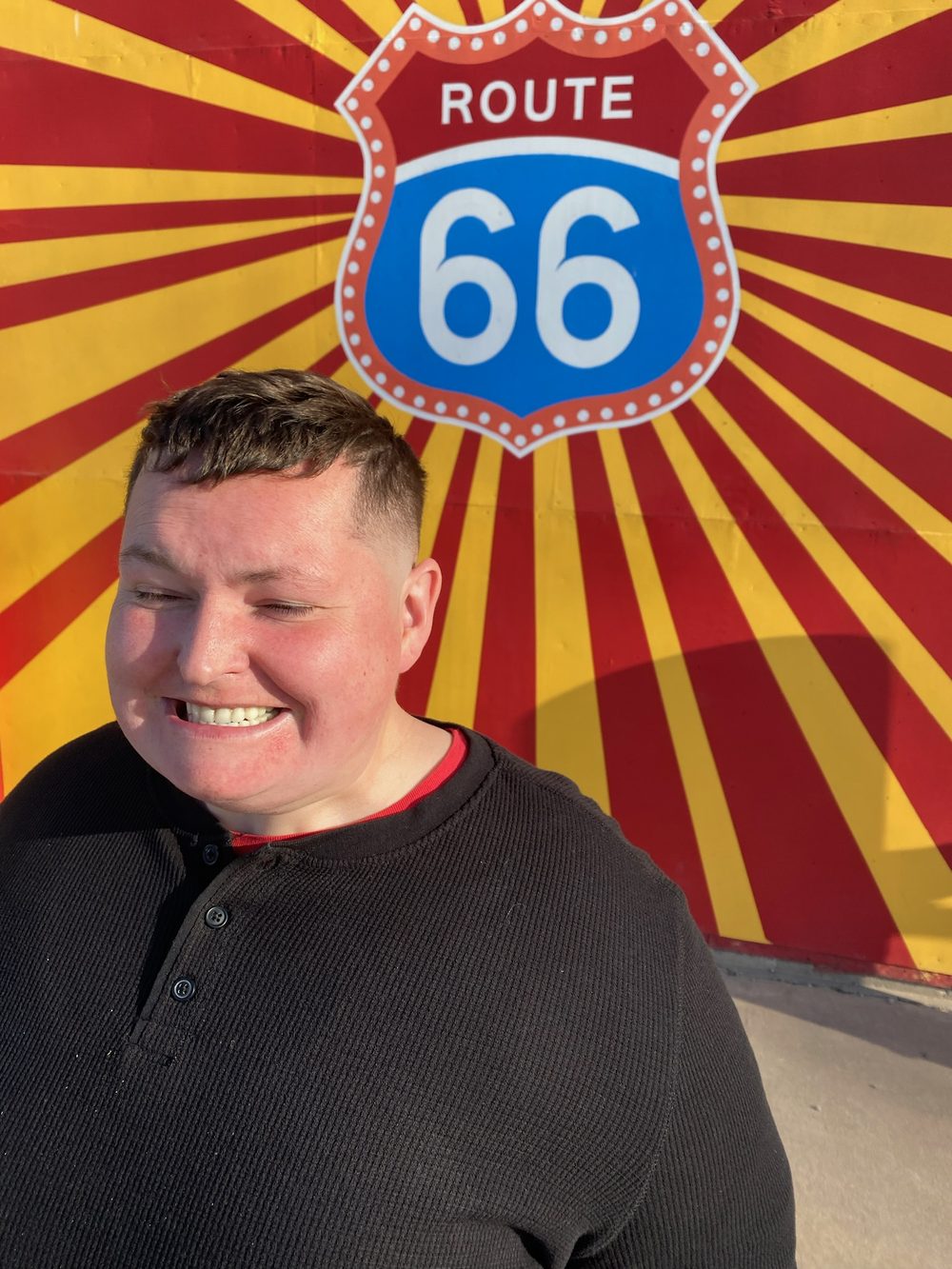 Amanda laughing in front of a painted Route 66 shield mural.