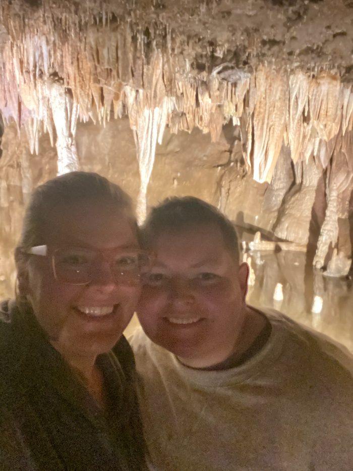 Amanda and Robyn underground beneath a ceiling of lit stalactites.
